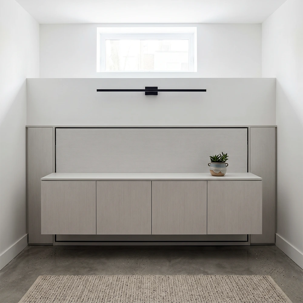 Full vs. Queen Wall Bed: 2026 Size Guide A minimalist modern horizontal Queen wall bed integrated into a low bulkhead wall within a space-efficient Montreal basement apartment.